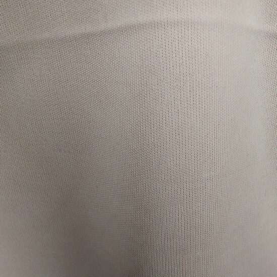 Close-up of beige fabric with fine texture and subtle weave pattern.